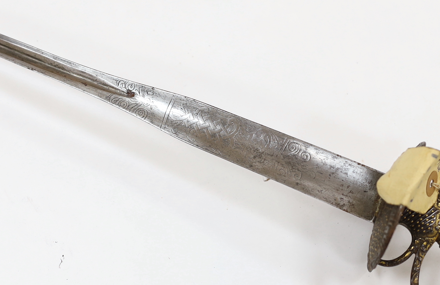 A French iron hilted small sword, hilt with flutes and tiny gold dots, the knuckle guard with key decoration, iron tape and silver wire bound grip, colichemarde blade with etched strapwork decoration, c.1770, blade 83cm